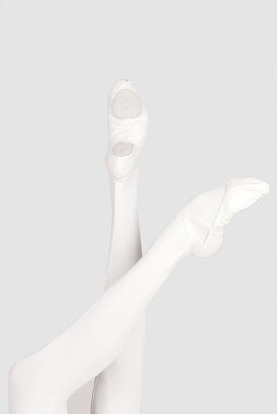 White ballet pointe shoes worn on crossed legs, shown against a light gray studio background.