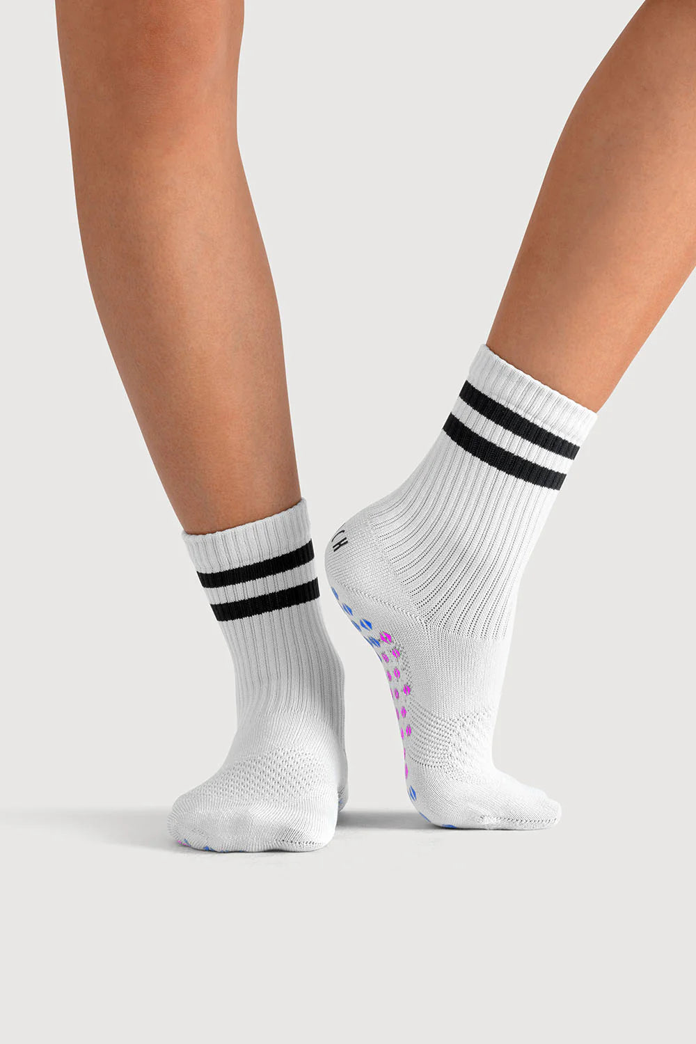 White socks with black stripes worn by a person on a light gray background