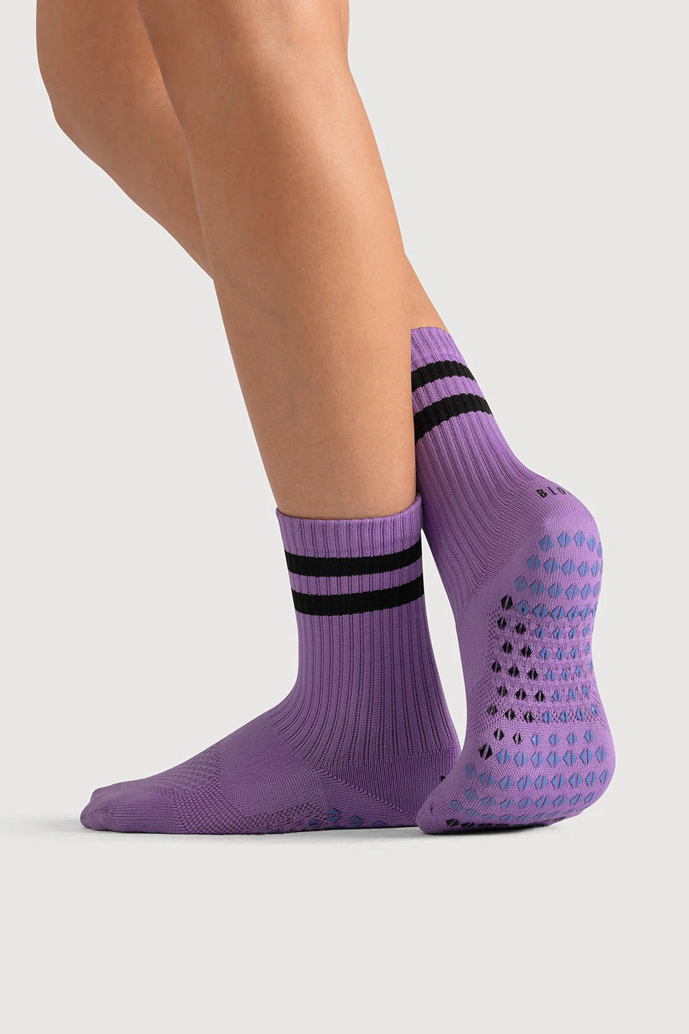 Purple socks with black stripes worn by a person on a light gray background