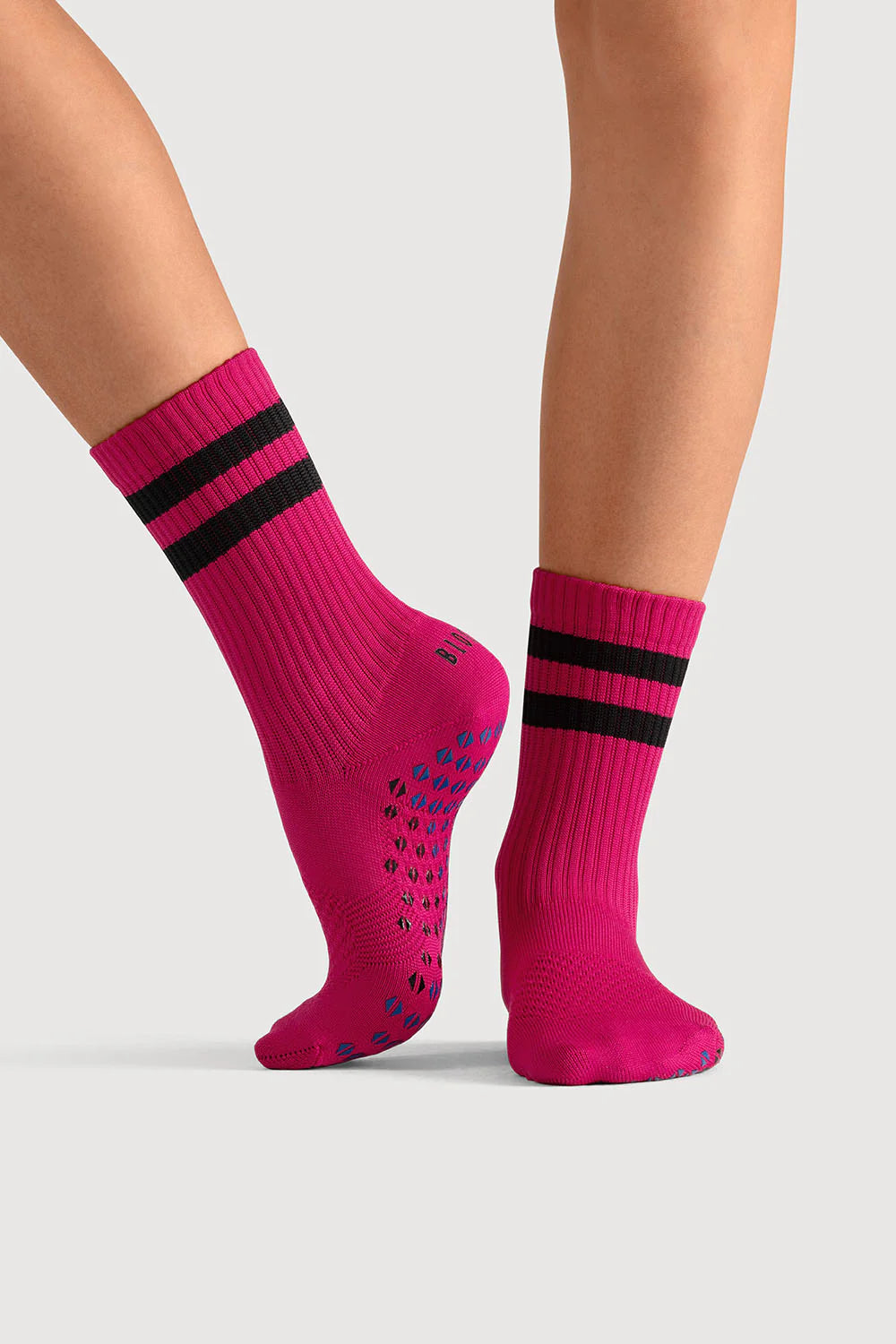 Pink socks with black stripes worn by a person on a light gray background