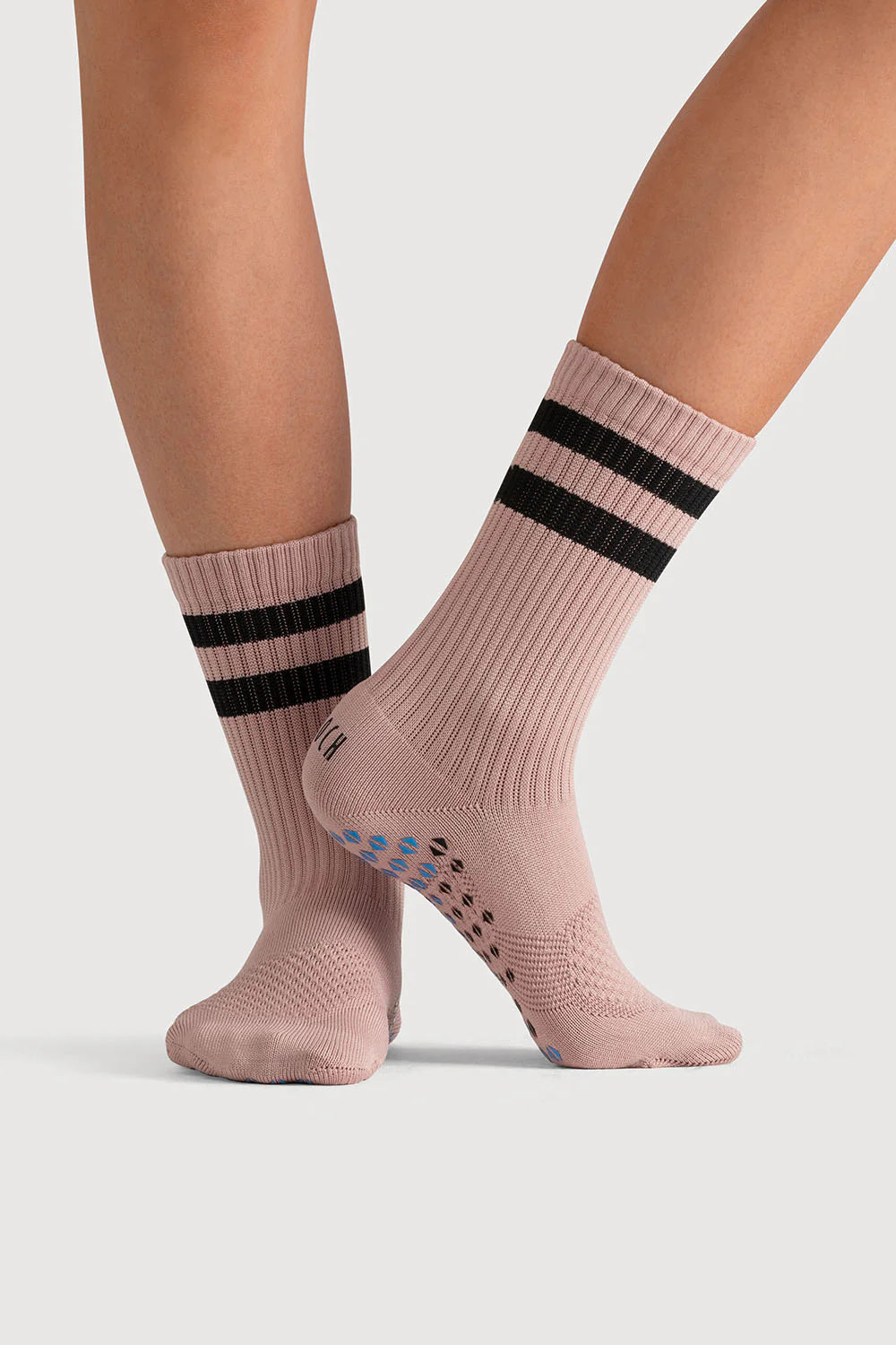 Pink socks with black stripes worn by a person on a light gray background