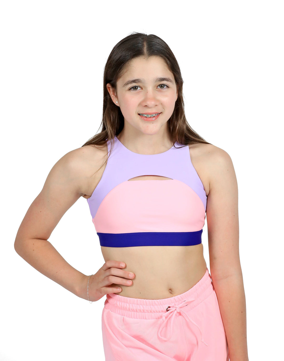 Young girl wearing a colorful sports bra and pink pants on a white background