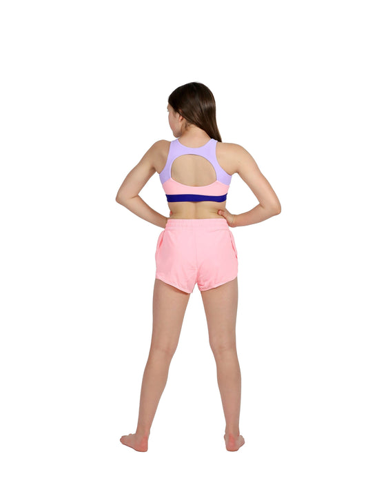 Woman wearing a pink sports bra and shorts set on a white background
