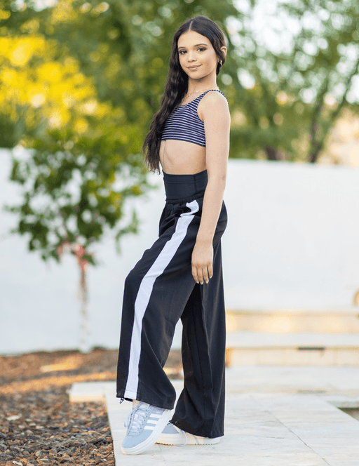 Woman wearing a black and white outfit with a blurred outdoor background