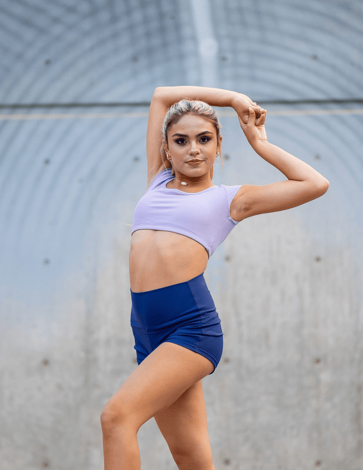 Woman in athletic wear posing outdoors against a textured wall.