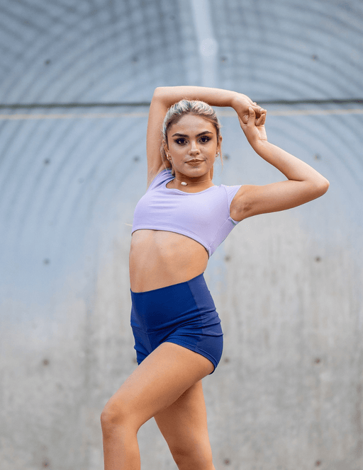 Woman in athletic wear posing outdoors against a textured wall.
