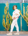 Person wearing a white outfit with pink accents standing in front of cacti.