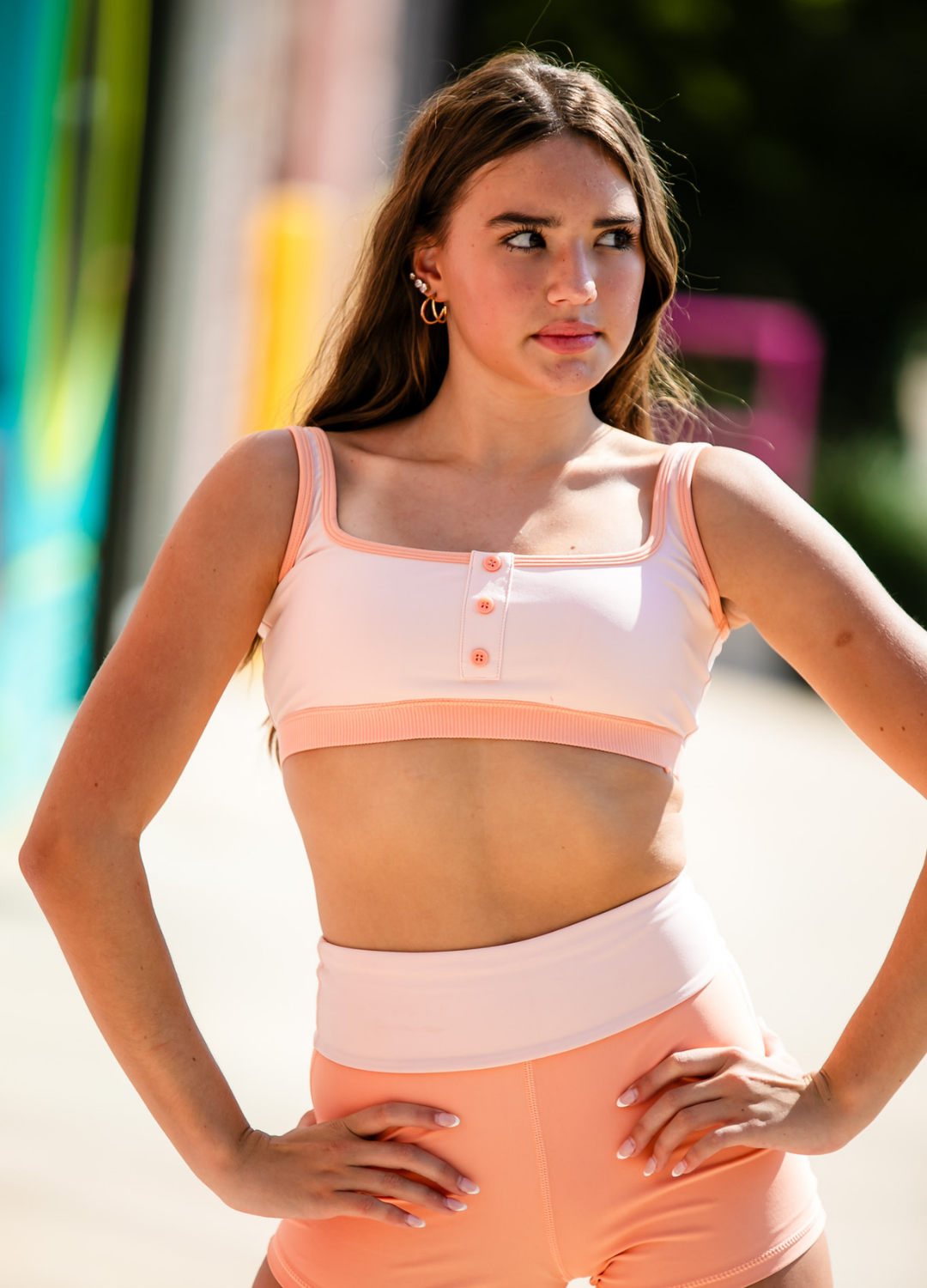 Woman wearing a pink sports bra and leggings with a blurred urban background
