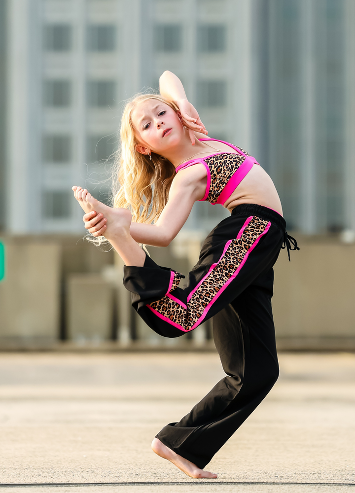 Dancer in a black and pink outfit performing outdoors with buildings in the background