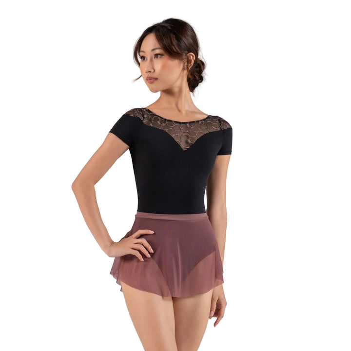 Woman wearing a black top with lace details and a brown skirt on a gray background