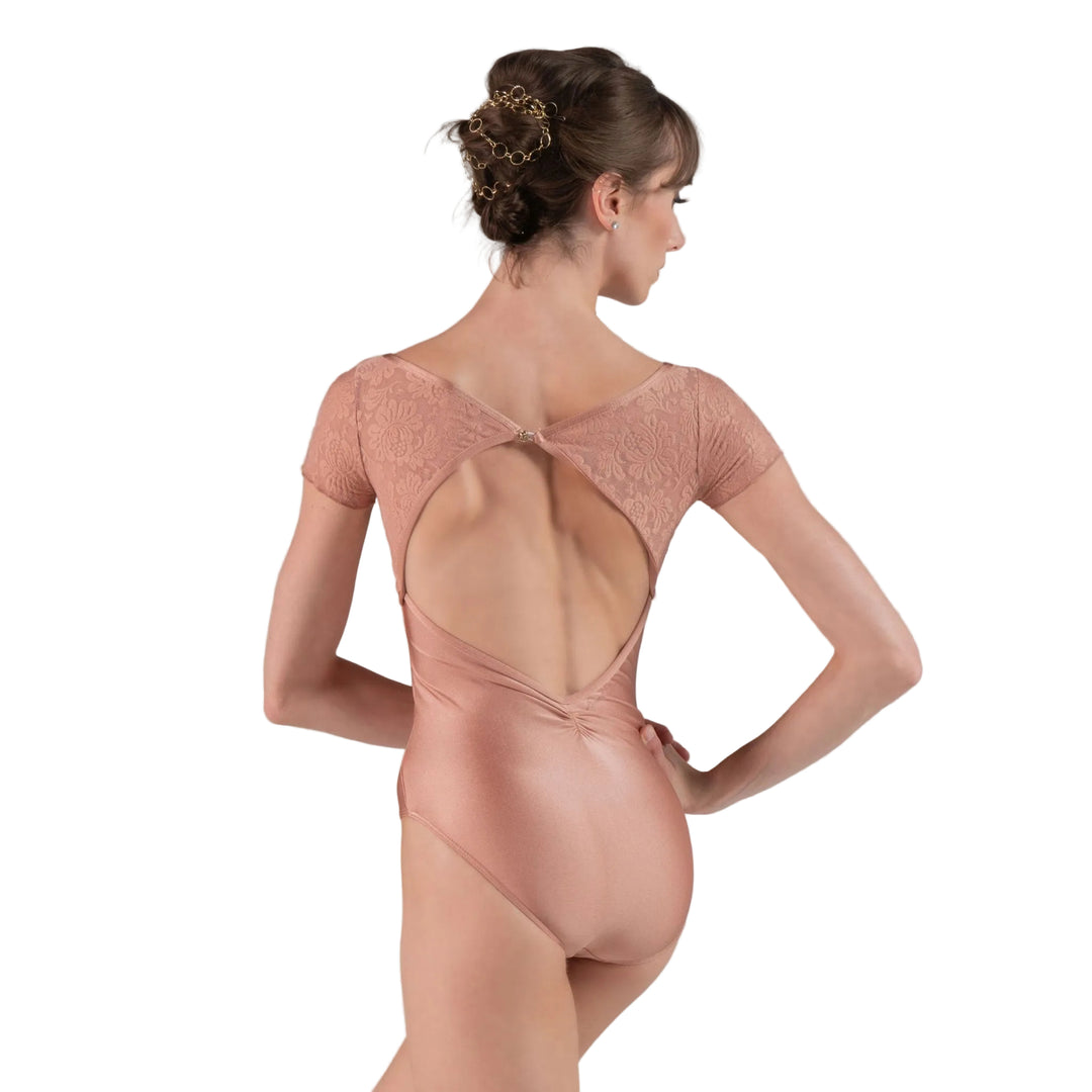 Ballerina in a pink leotard with open back on a gray background