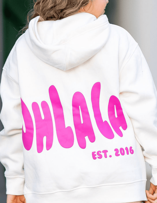 White hoodie with pink 'OH LA LA' text on the back, worn by a person.