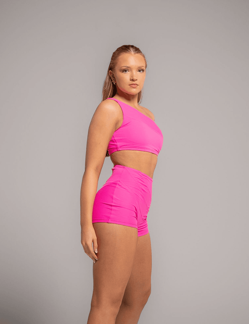Woman wearing a bright pink two-piece outfit on a gray background