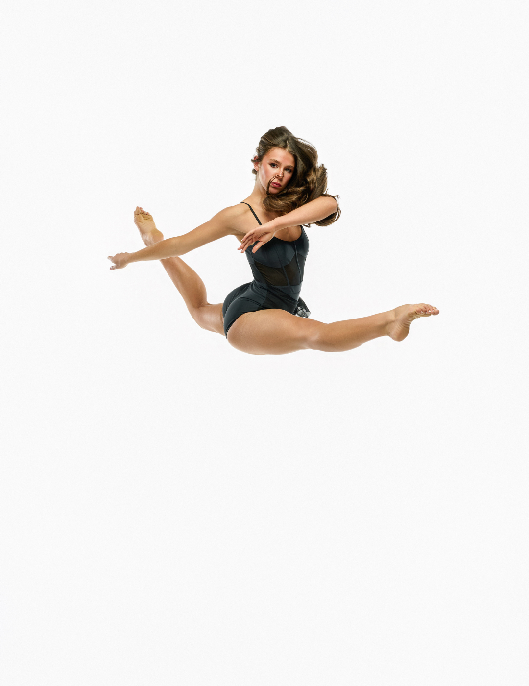 A woman in a black leotard performing a high split leap against a solid white background.