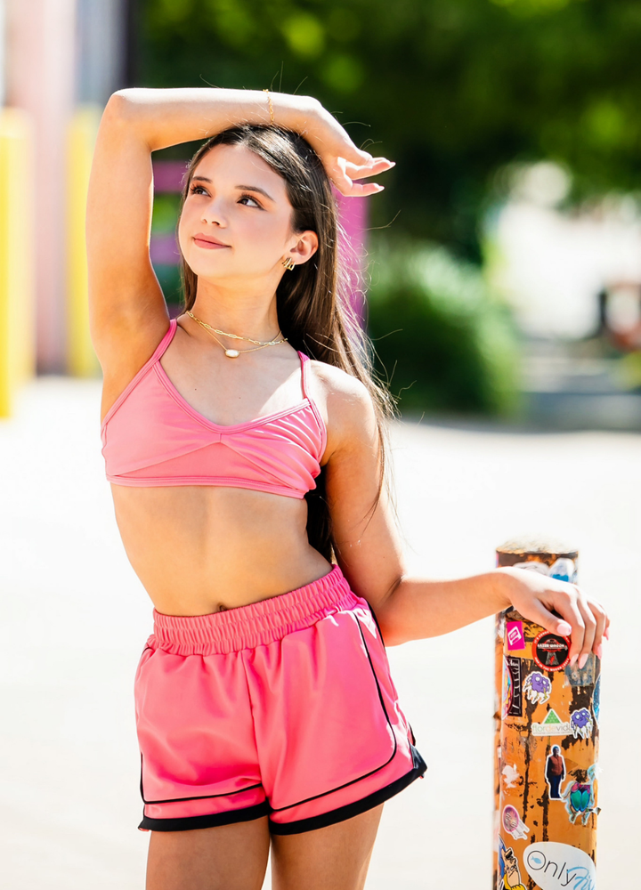 Woman in pink athletic wear holding a skateboard outdoors