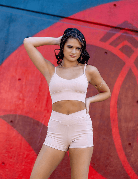 Woman in a pink sports outfit posing against a colorful abstract background