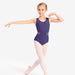 Young girl in a purple leotard and white tights posing on a white background