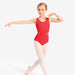 Young girl in a red leotard and white tights posing on a white background