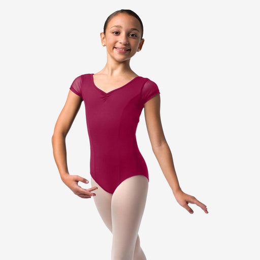 Young girl in a maroon leotard and white tights on a plain background