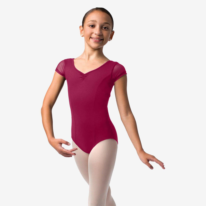 Young girl in a maroon leotard and white tights on a plain background