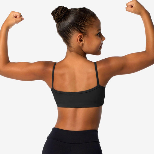Woman flexing her muscles wearing a black sports bra and leggings on a white background