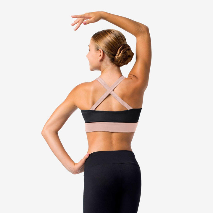 Woman wearing a black and beige sports bra with a plain background
