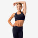 Woman wearing a black sports bra and leggings on a white background