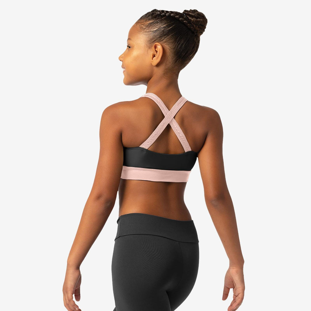 Woman wearing a black sports bra with pink straps on a white background