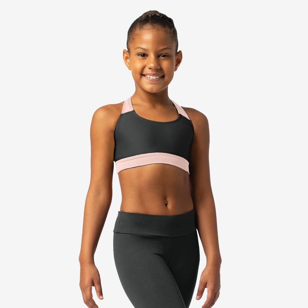 Young girl wearing a black sports bra with pink straps and black leggings on a white background