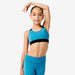 Young girl wearing a blue sports bra and leggings on a white background
