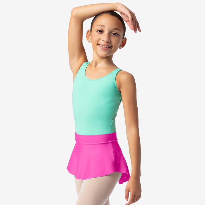 Young girl in a green top and pink skirt posing against a white background