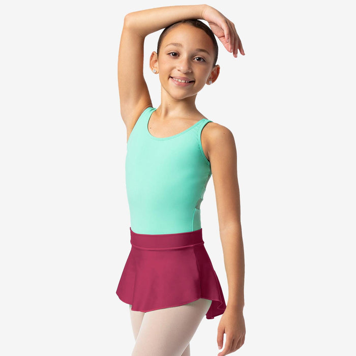 Young girl in a green top and pink skirt posing against a white background