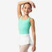 Young girl in a green leotard and white skirt posing against a white background