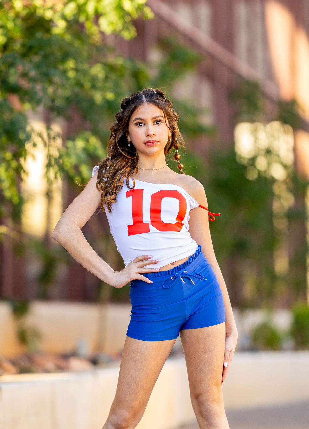 Woman wearing a white tank top with the number 10 and blue shorts outdoors.