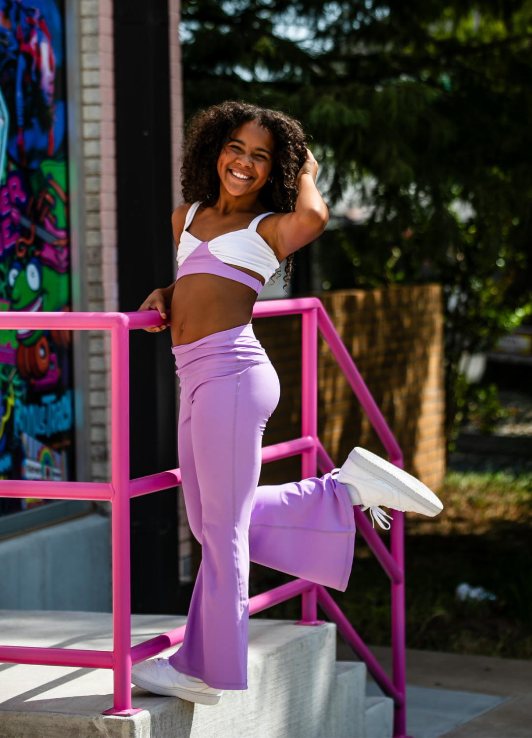 Woman in purple athletic outfit standing on a staircase with graffiti in the background