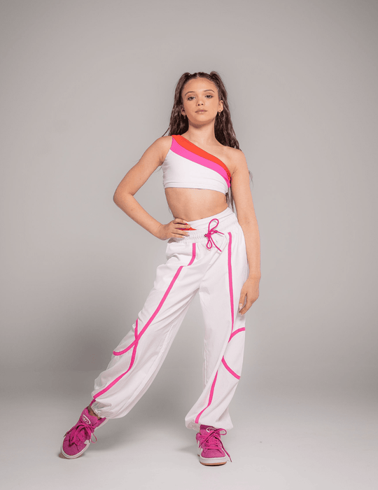 Person wearing a white and pink outfit with a crop top and high-waisted pants on a gray background