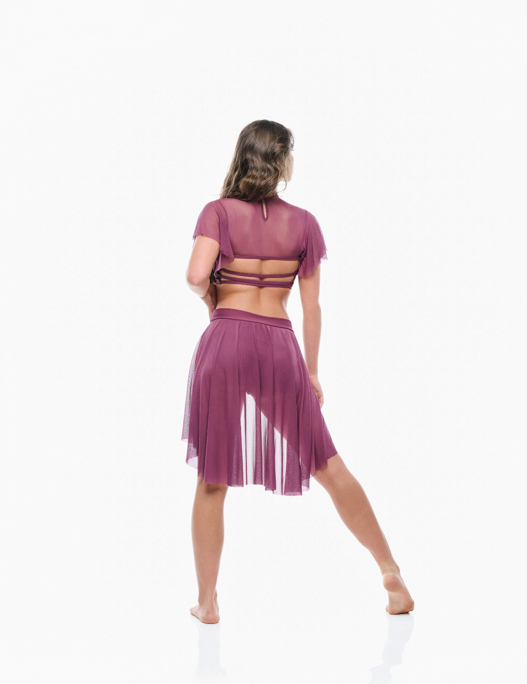 Woman wearing a purple outfit with a sheer top and skirt on a white background