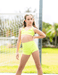 Young girl in a bright yellow sports outfit standing outdoors with greenery in the background