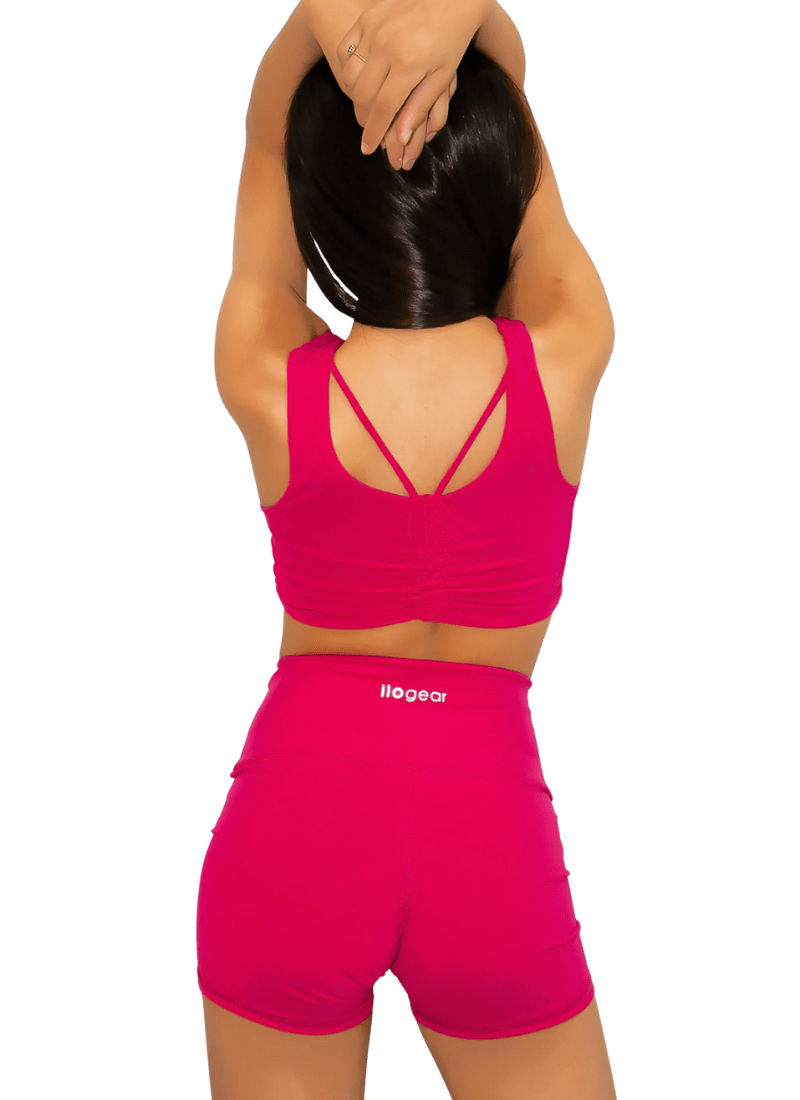 Person wearing a pink sports bra and shorts set with 'illegear' branding on a white background