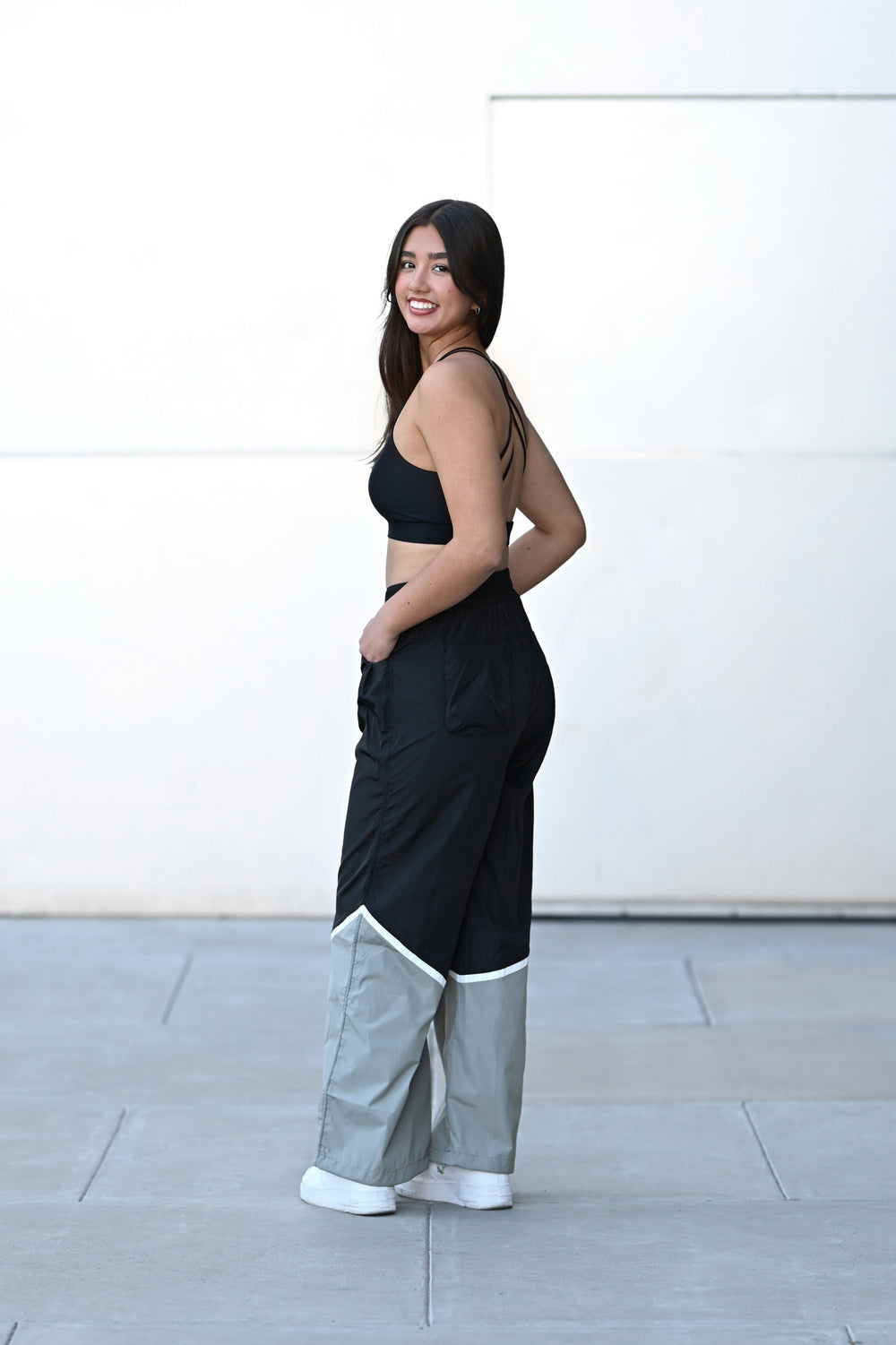 Woman wearing a black top and wide-leg pants with a white background