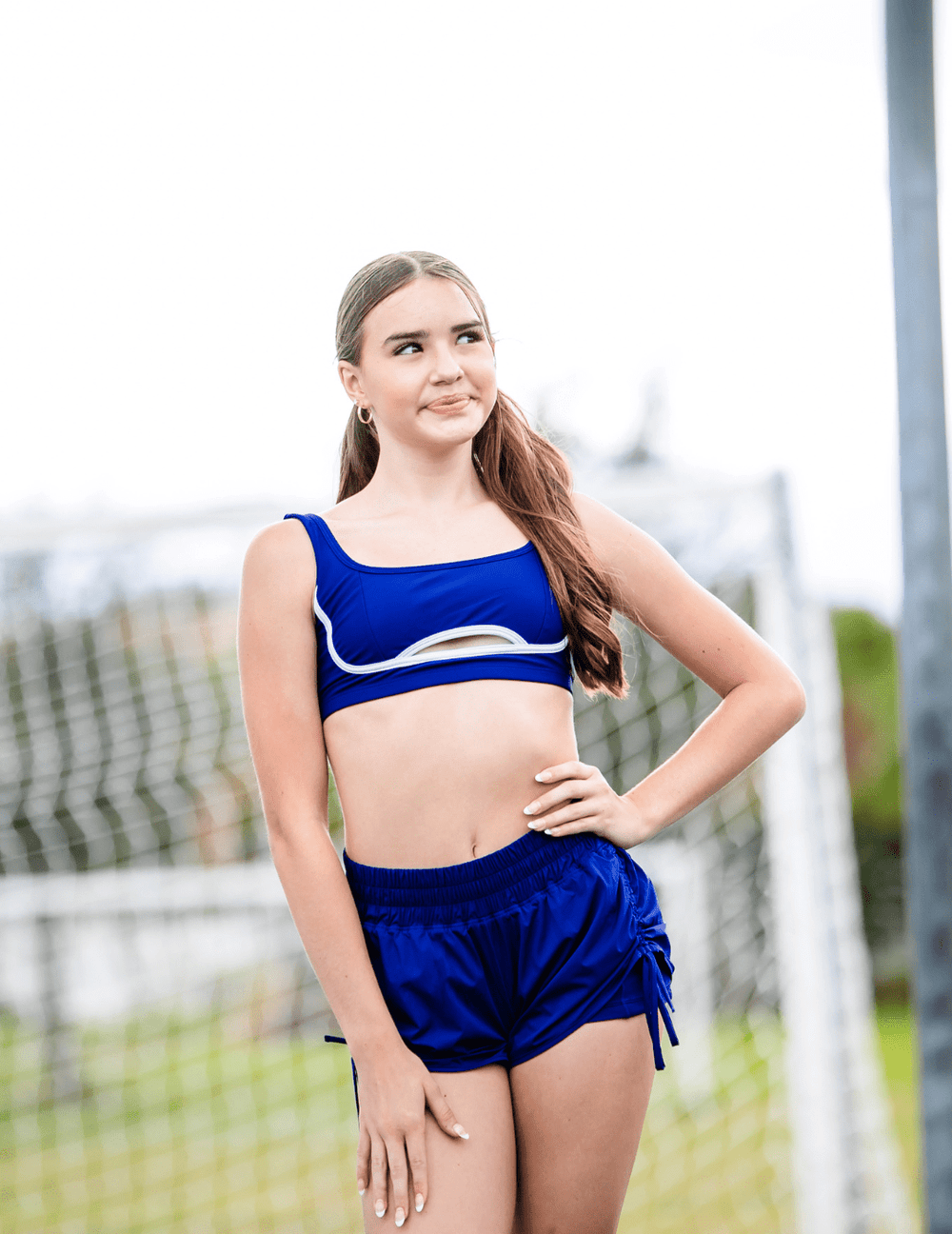 Woman wearing a blue sports outfit standing outdoors with a blurred background