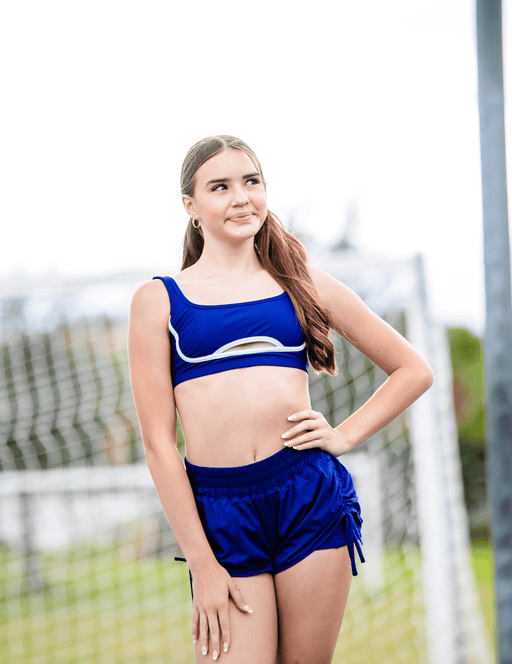 Woman wearing a blue sports outfit standing outdoors with a blurred background