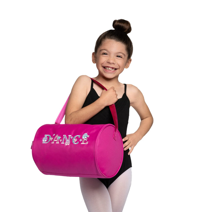 Young girl in a dance outfit holding a pink 'DANCE' bag on a white background