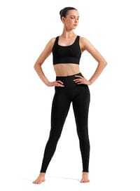 Woman wearing a black sports bra and leggings on a white background