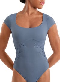 Woman wearing a blue bodysuit with cap sleeves on a white background