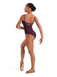Dancer wearing a dark purple leotard with thin straps on a white background