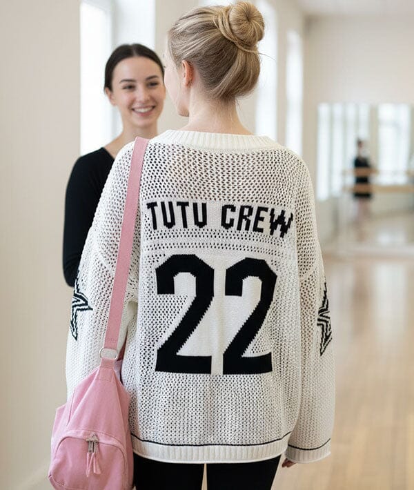 Person wearing a sweater with 'Tutu Crew 22' text, holding a pink bag.