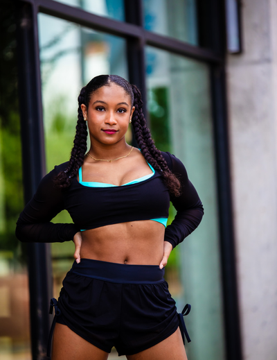 Woman in athletic wear standing outdoors with a blurred background