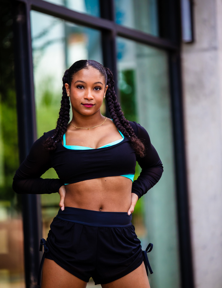 Woman in athletic wear standing outdoors with a blurred background
