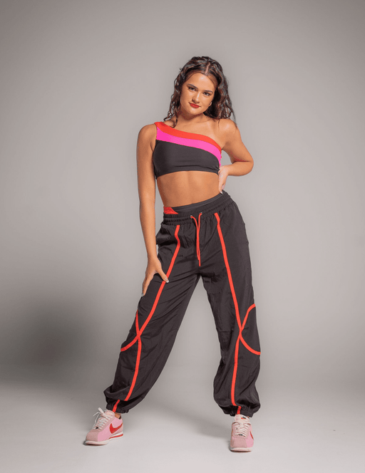Woman wearing a black and pink sports outfit with high-waisted pants on a gray background